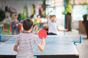 Kind mit Eltern übt gemeinsam Tischtennis