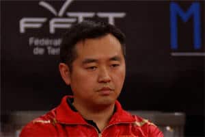 Mann in roter Jacke bei Tischtennis-Pressekonferenz in Frankreich, konzentriert, vor „FFTT“-Logo.