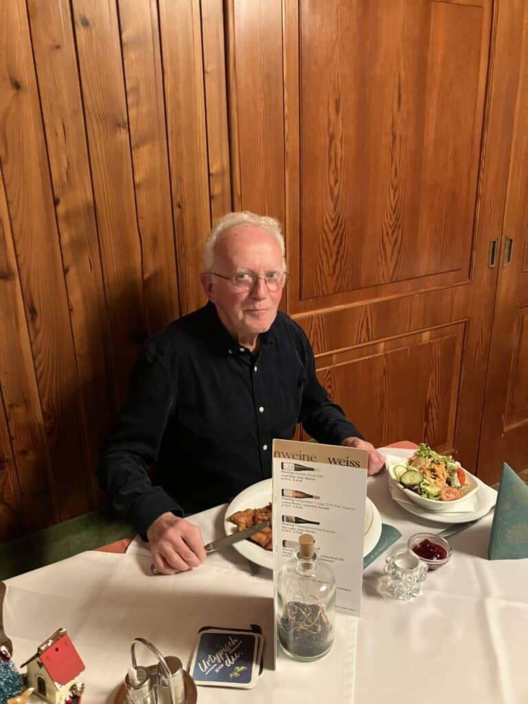 Ein älterer Mann genießt alleine ein gemütliches Abendessen in einem festlich dekorierten Restaurant.