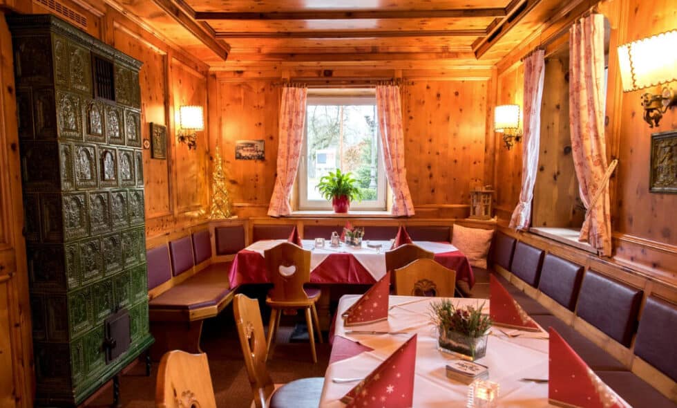 Tischtennis Leonding | Bilder „Tischtennis Leonding“ Gemütliches Alpen-Esszimmer aus Holz mit Kachelofen, festlichem Tisch und herzförmigen Stühlen.