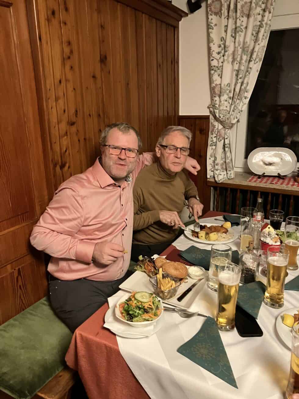 Gemütliches Abendessen von zwei Männern in rustikalem Restaurant mit Bier und köstlichen Speisen.
