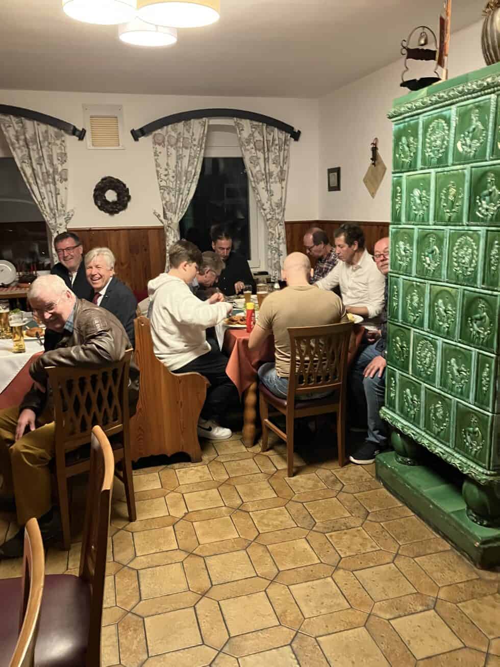 Gemütliches Beisammensein mit Kachelofen in traditionellem österreichischem Gasthaus, herzliche Atmosphäre.