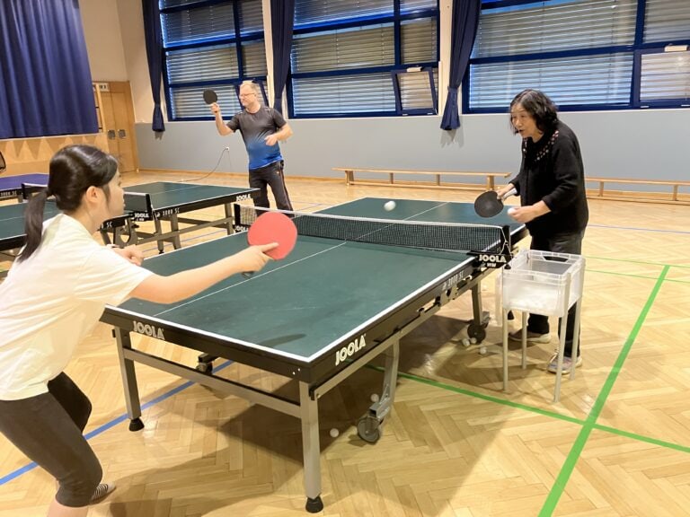 Tischtennis-Trainingsspiel: Zwei Frauen, Ballwechsel im Sportzentrum, intensives konzentriertes Training.
