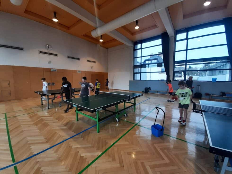 Tischtennis-Training für Jugendliche in geräumiger, lichtdurchfluteter Turnhalle mit JOOLA-Tischen.