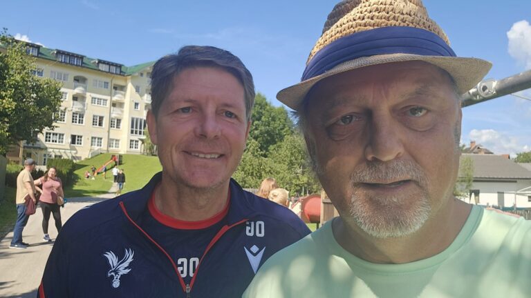 Tischtennis Leonding | Bilder „Tischtennis Leonding“ Zwei Männer genießen einen sonnigen Tag im Freien vor einem schönen Gebäude.