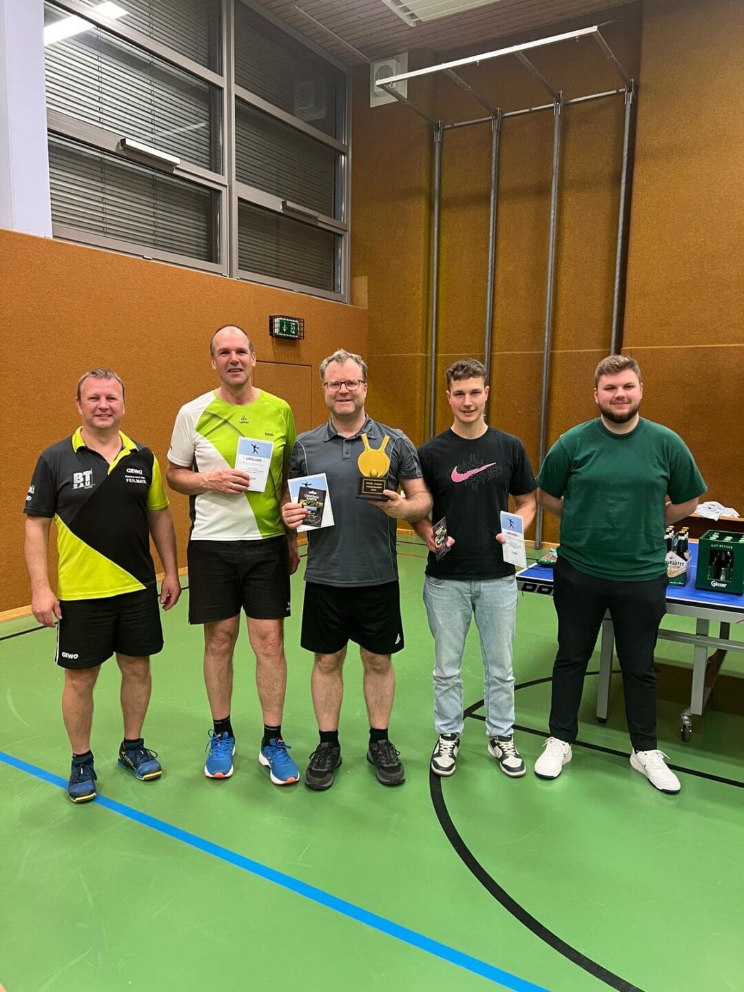Bilder von unseren Mitgliedern Sportler bei Preisverleihung im Turnsaal, feiern Erfolge mit Trophäen und Urkunden.