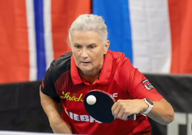 Tischtennisspielerin in Aktion, bereit für den nächsten Schlag im Wettkampf.