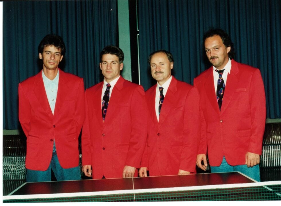 Tischtennis Leonding | Bilder „Tischtennis Leonding“ Vierter Herren in roten Blazern stehen hinter einem Tischtennistisch für Teambild.
